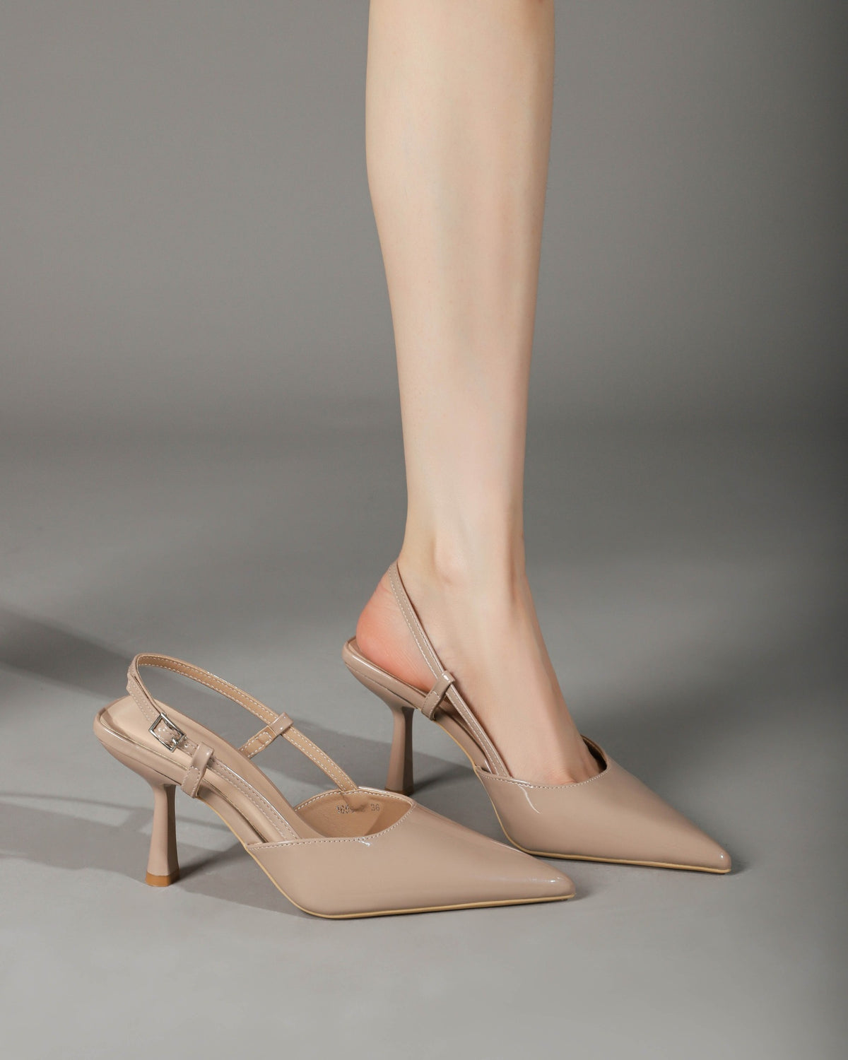 Khaki patent pointed-toe slingback pumps on foot 1