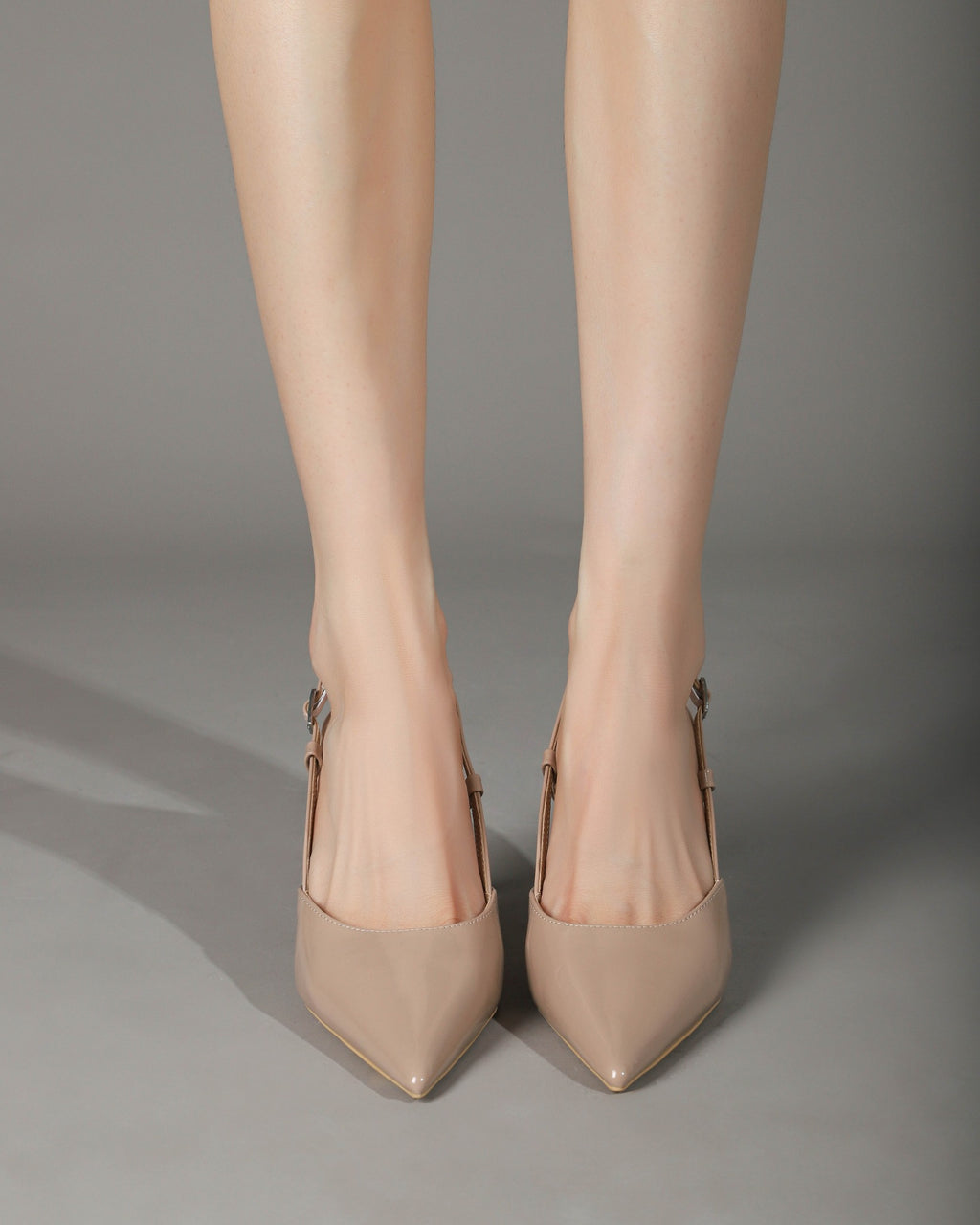 Khaki patent pointed-toe slingback pumps on foot 2