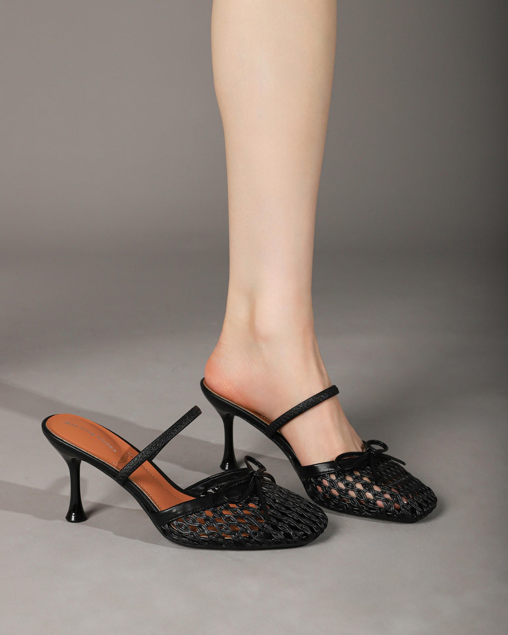 Black woven bow mules worn, single shoe and side view