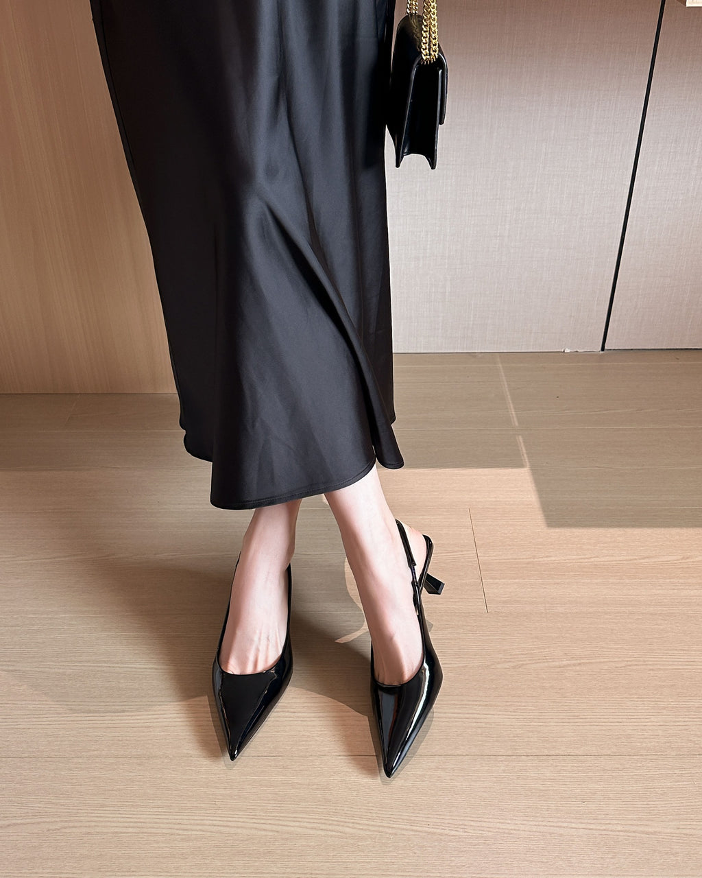 Black pointed-toe patent slingback pumps on foot