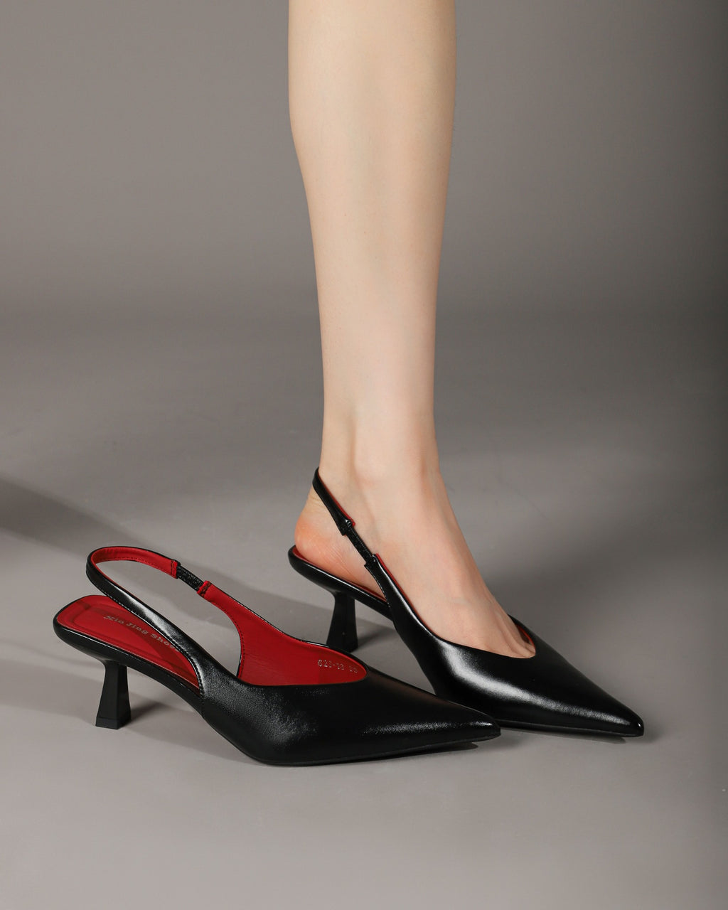 Black pointed-toe slingback heels modeled with one shoe alongside