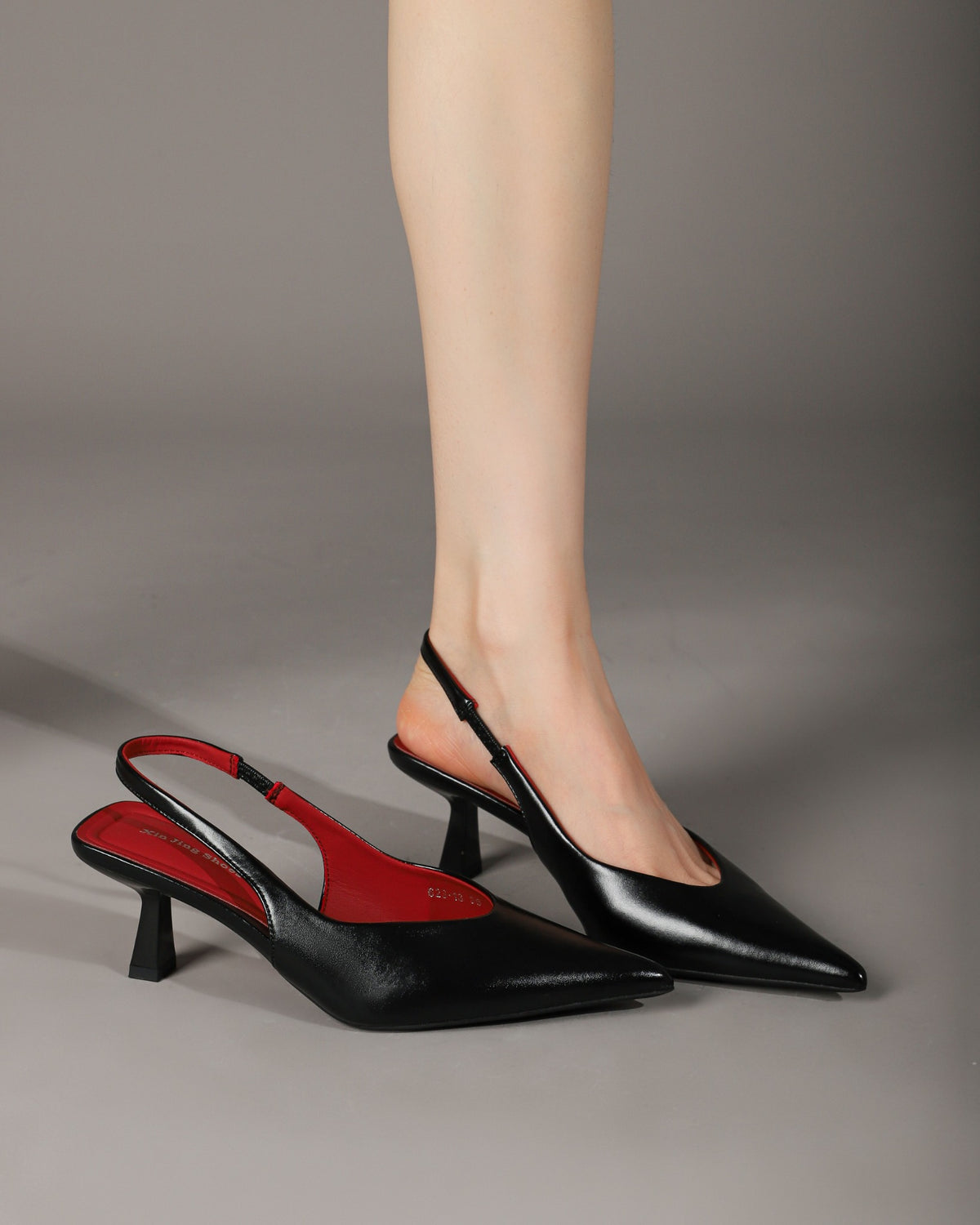 Black pointed-toe slingback heels modeled with one shoe alongside