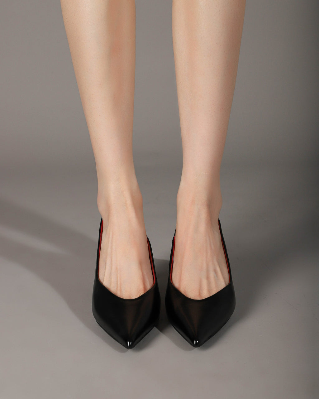 Black pointed-toe slingback heels modeled front view