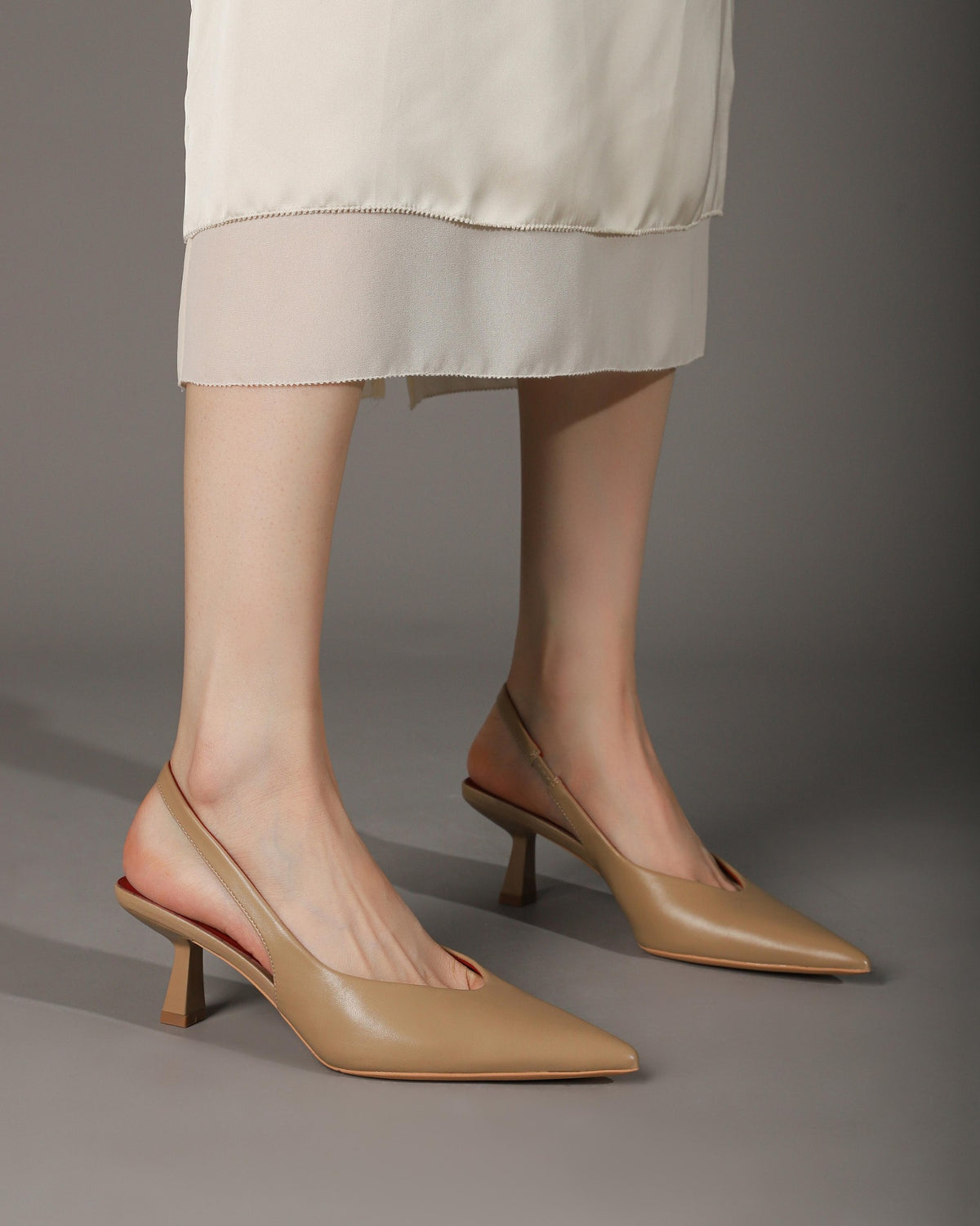 Khaki pointed-toe slingback heels modeled side view