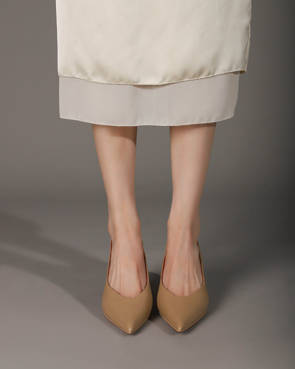 Khaki pointed-toe slingback heels modeled front view