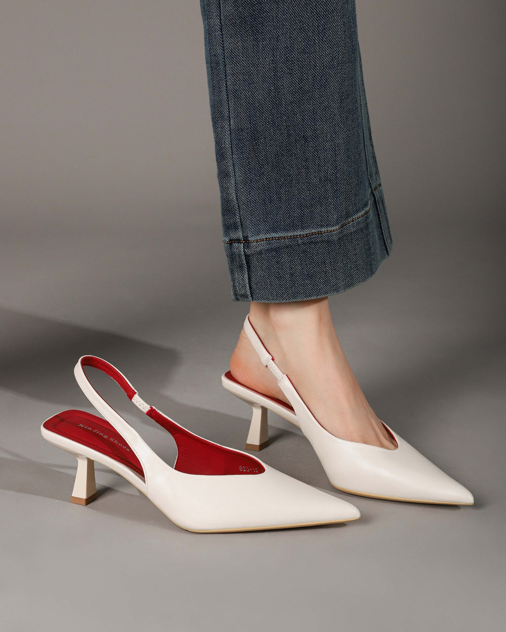 Off-white pointed-toe slingback heels modeled with one shoe alongside