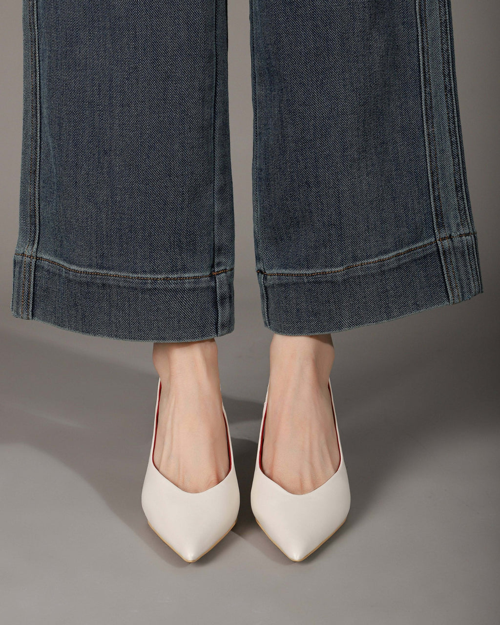 Off-white pointed-toe slingback heels modeled front view
