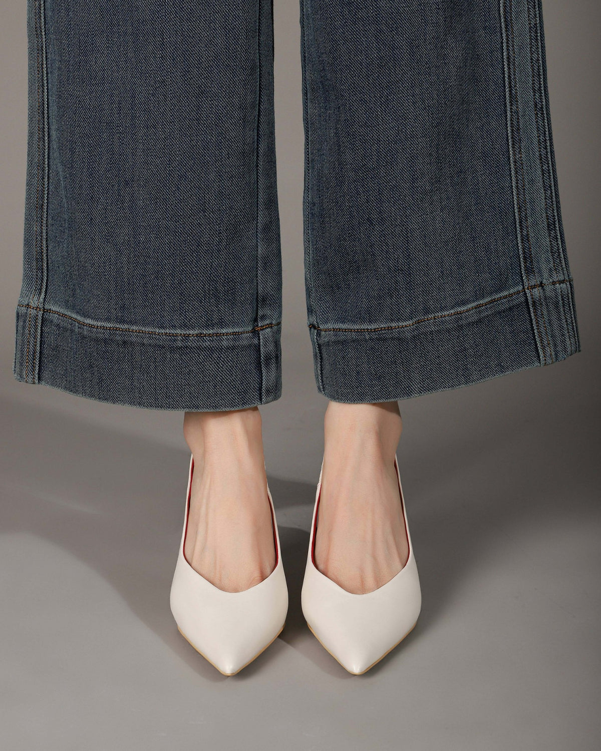 Off-white pointed-toe slingback heels modeled front view