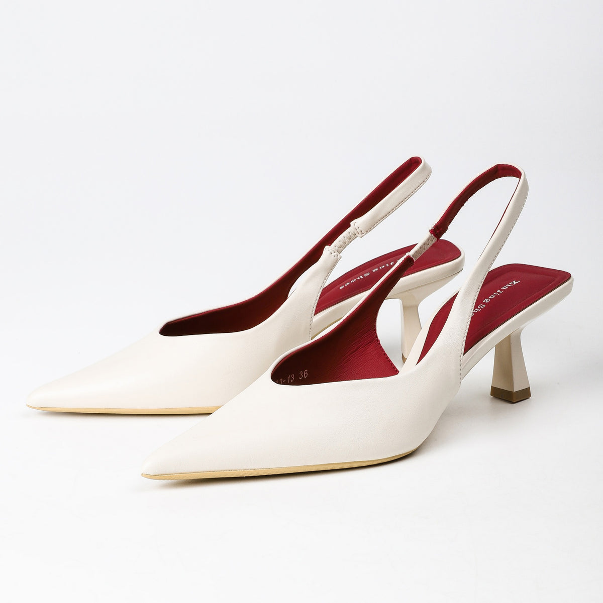 Off-white pointed-toe slingback heels pair studio view