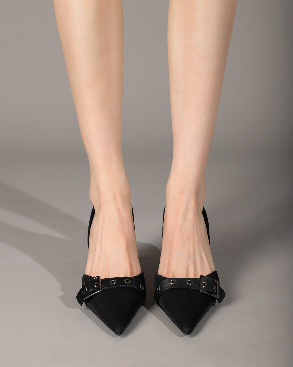 Black pointed-toe slingback heels on foot front view
