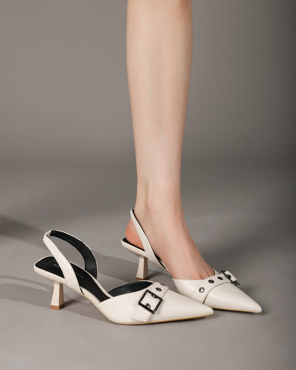 Off-white slingback heels on foot seated side view