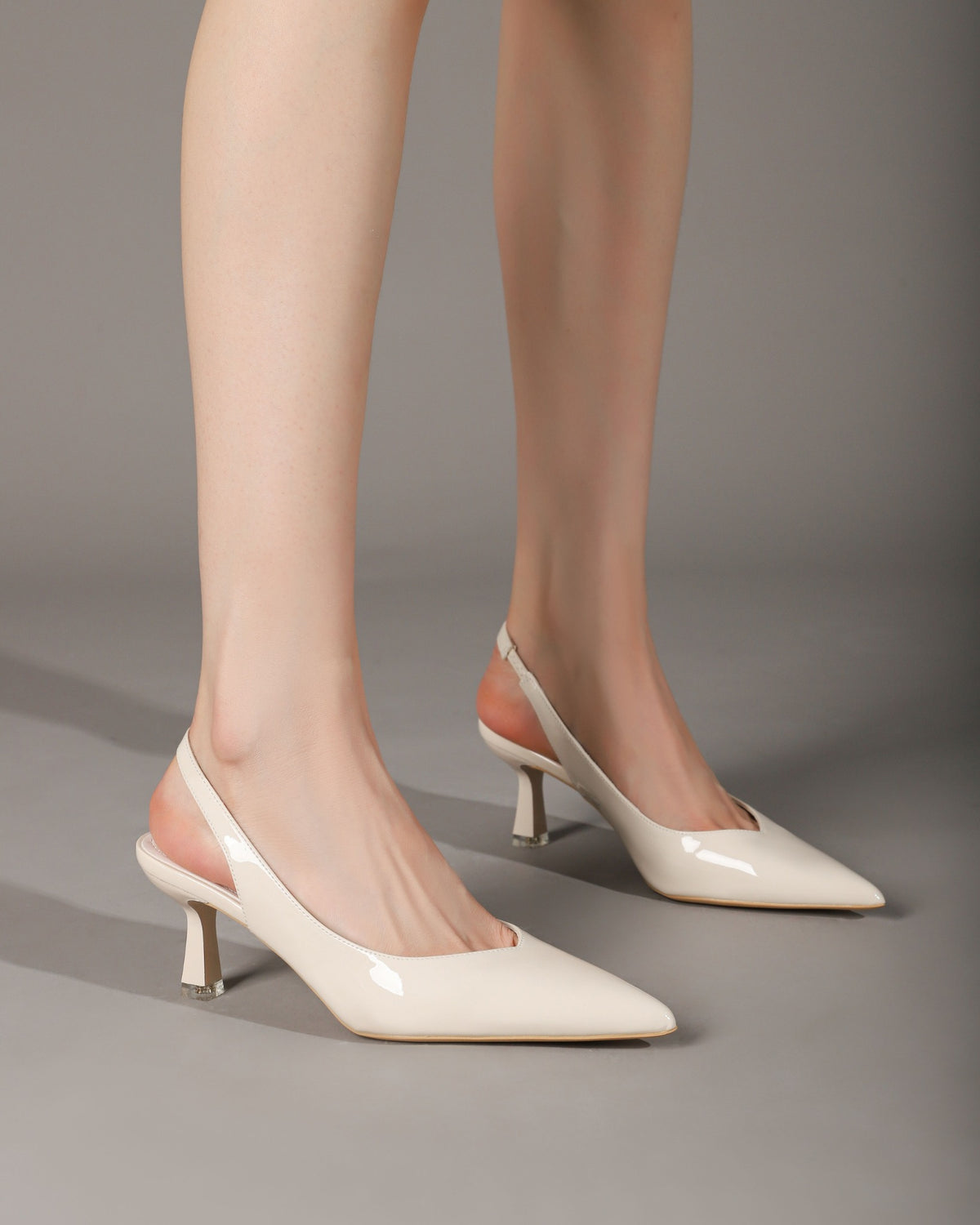 Cream patent slingback heels worn by model seated