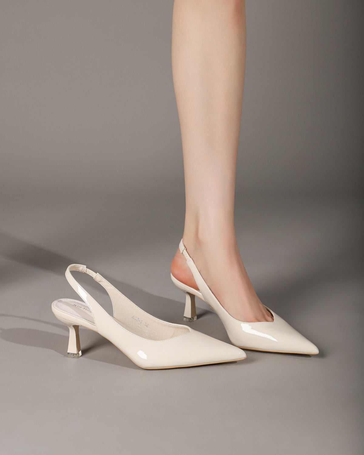 Cream patent slingback heels on model front view